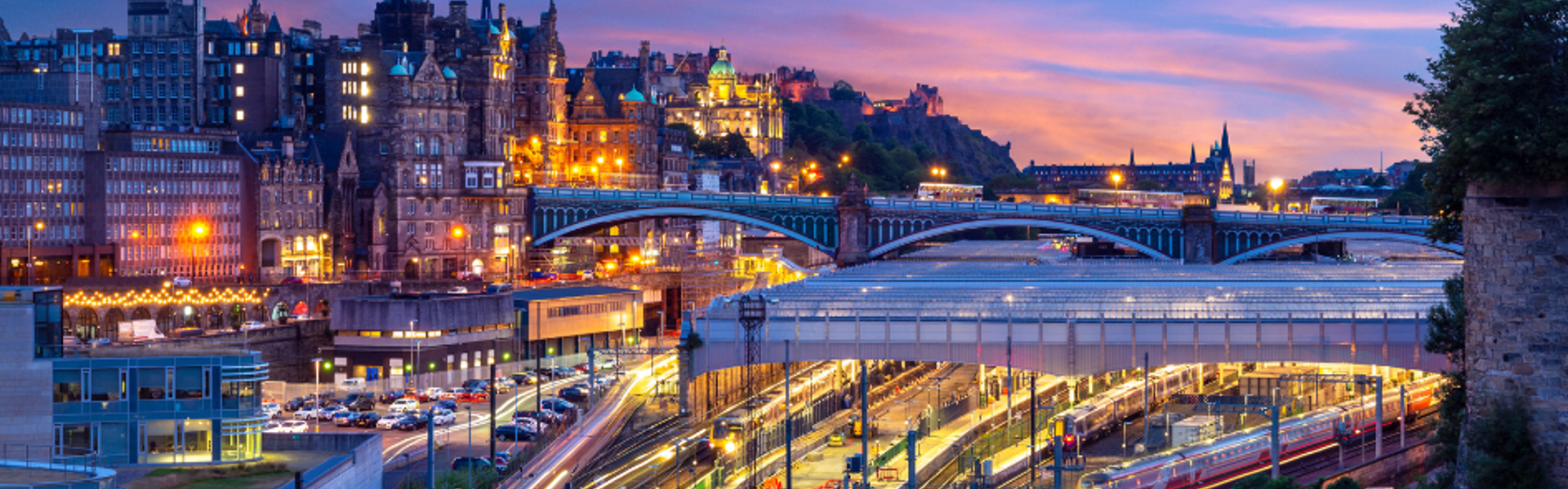 Trains leaving and arriving at a train station at dusk